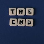 Scrabble tiles spelling 'The End' on a minimalist blue background. Perfect for conceptual designs.